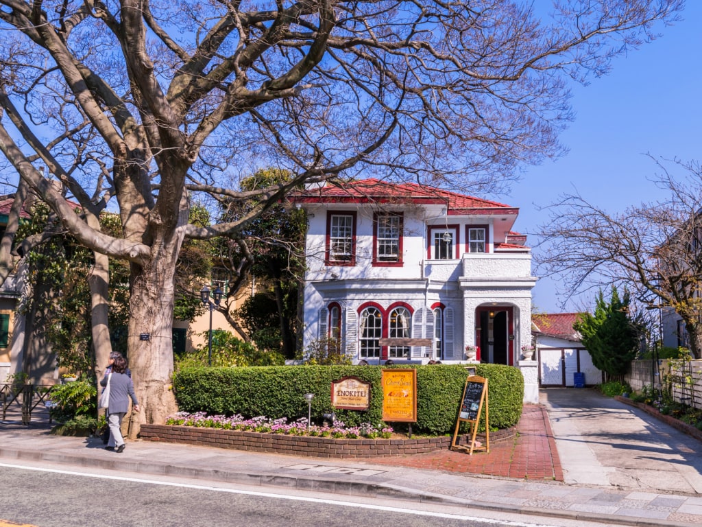 Maison blanche à toit rouge avec grand arbre