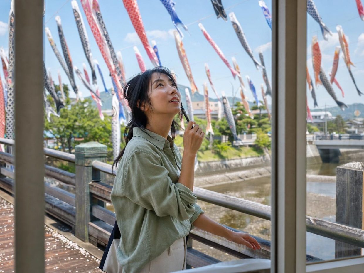 Femme regardant des koinobori au-dessus d’un pont