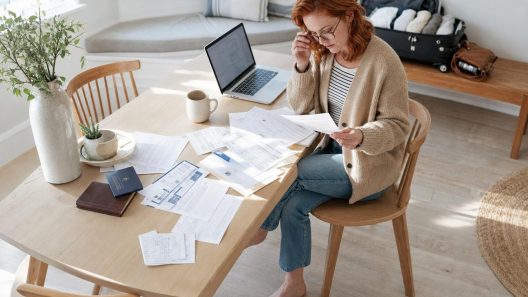 Femme examinant des documents à table avec valise