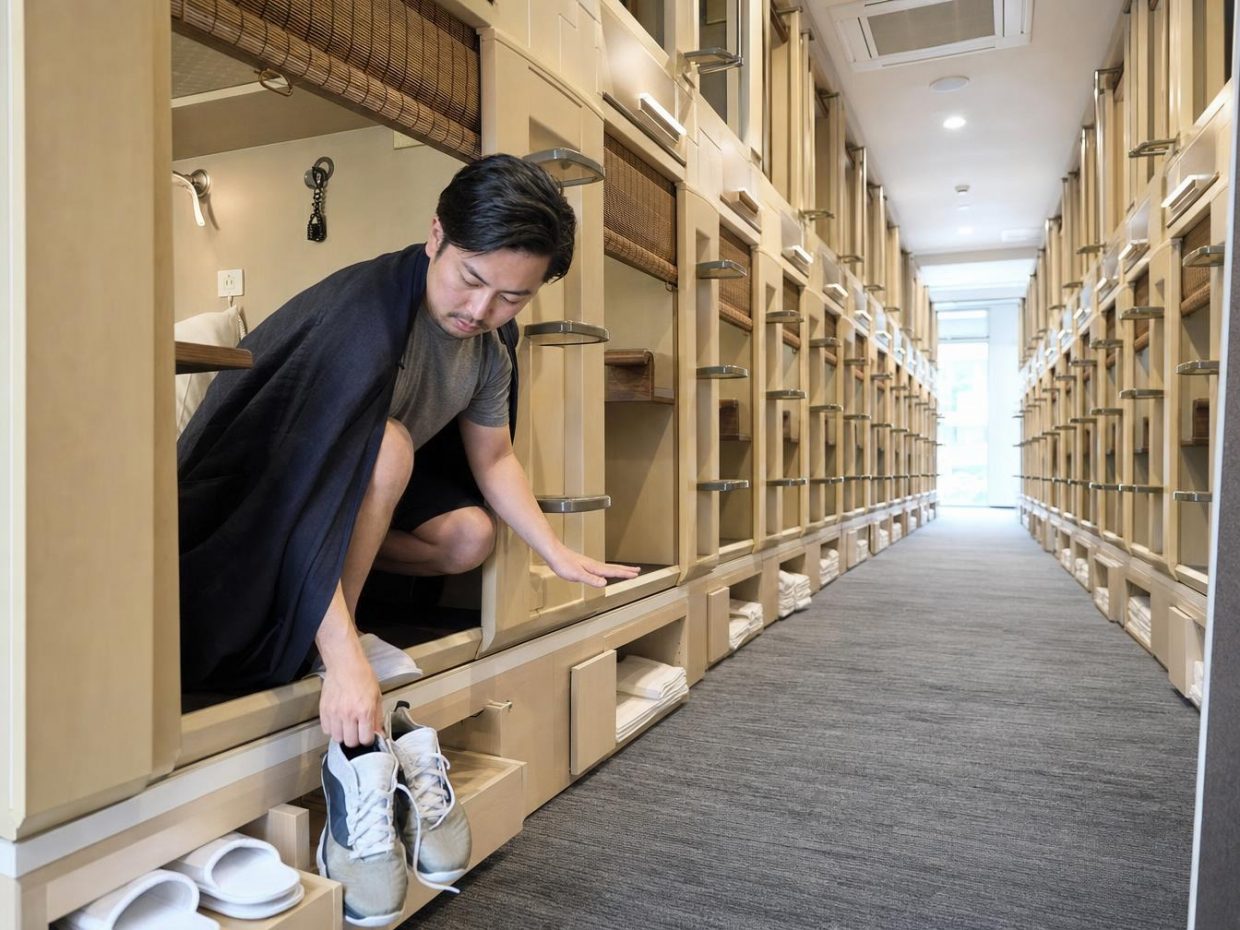 Homme dans un hôtel capsule enfile ses chaussures