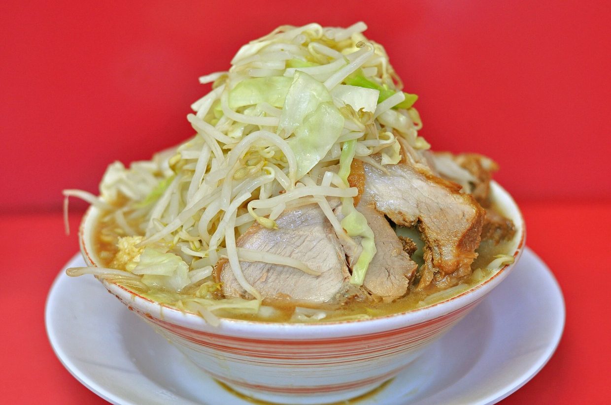 Bol de ramen de style Jiro couronné d'une montagne de moyashi et de chou, avec des tranches de porc